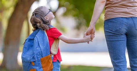 Matka podáva ruku dieťaťu pred budovou škôlky