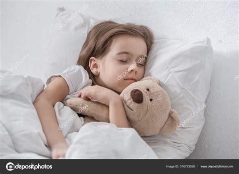 dievčatko spí v posteli s plyšovou hračkou