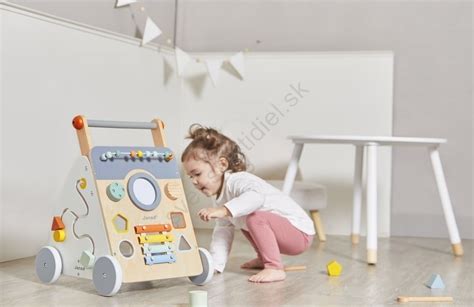 Dievčatko sa hrá s dreveným kočíkom v záhrade