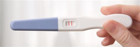 Žena drží v ruke tehotenský test s dvoma čiarkami