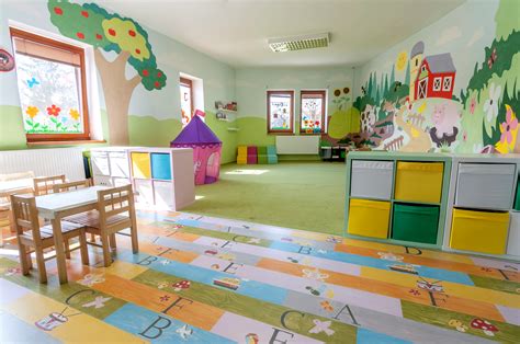 Interiér detských jaslí s deťmi hrajúcimi sa.