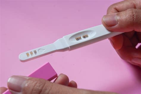 Žena drží v ruke tehotenský test