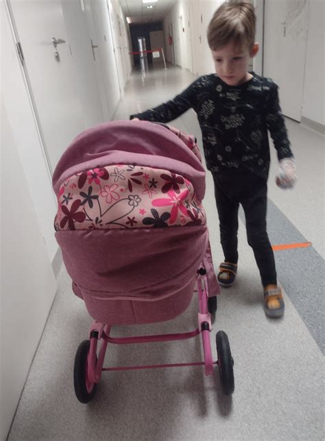 Dievčatko sa hrá s bábikou a kočíkom v interiéri